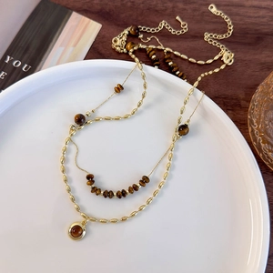 Detailed view of layered golden tiger eye stone necklace on a white ceramic plate