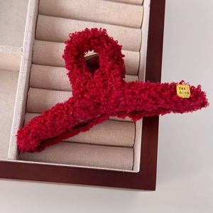 Vue détaillée de la pince à cheveux en peluche rouge avec étiquette dorée fashion