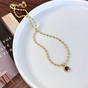 Detailed macro view of double-layered gold bead chain necklace with tiger eye stone pendant