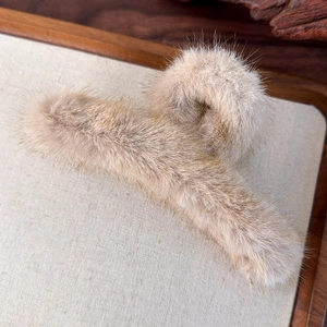 Dettaglio della morbida trama in peluche su una molletta per capelli color marrone chiaro