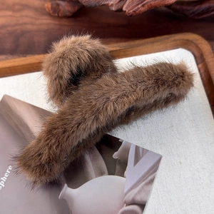 Macro di una morbida molletta per capelli in peluche marrone su un vassoio di legno decorativo