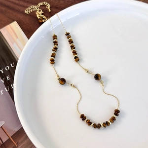 Detail of tiger eye stone beads and gold metal accents on double-layer necklace chain