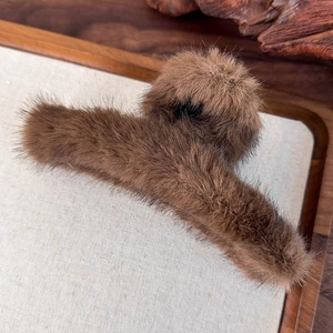 Dettaglio di una molletta per capelli in peluche marrone su un vassoio autunnale