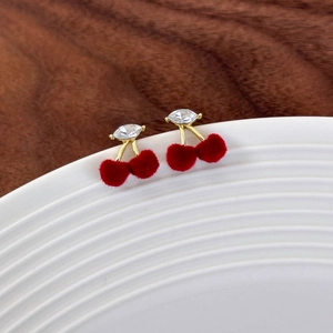 Sweet cherry stud earrings with red velvet fruit and gold leaf details on a ceramic dish