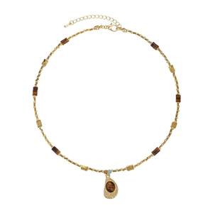 Detail of tear-drop tiger eye pendant with intricate golden filigree on a beaded chain