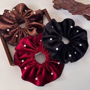 Close-up of vintage velvet scrunchies with white pearls in brown, burgundy, and black