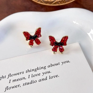 Macro shot of vintage red crystal butterfly earrings on a white decorative ceramic plate