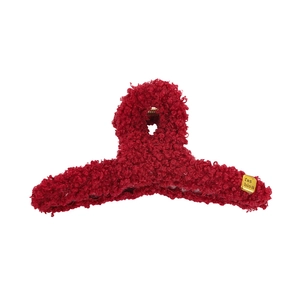Détail d'une pince à cheveux en peluche rouge foncé avec plaque dorée fashion