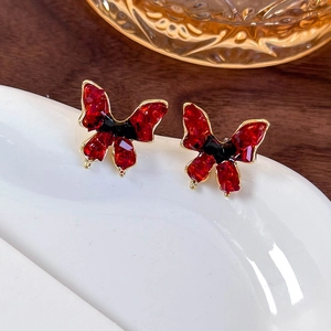Close-up of vintage red crystal butterfly earrings on a white ceramic plate