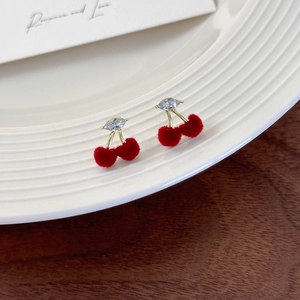 Macro view of cute cherry stud earrings with red velvet texture and sparkling zircon leaves