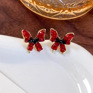 Vintage butterfly earrings with red crystals and gold trim on white ceramic tray