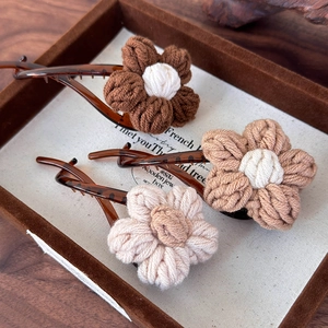 Set de trois barrettes à fleurs tricotées en café et beige sur un plateau à bijoux
