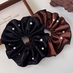 Close-up of elegant black and coffee velvet hair scrunchies with white faux pearls detail