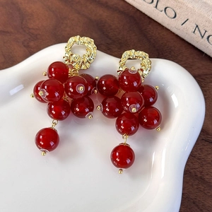 Detail view of vintage red beaded cluster grape tassel earrings with gold metal accents