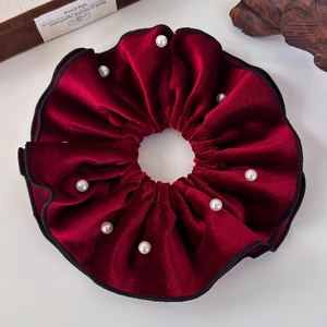 Detailed view of vintage red velvet scrunchie with faux pearls and black piping trim