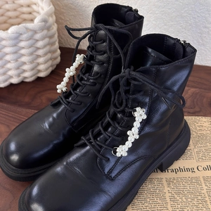 Close-up of black leather platform boots featuring stylish pearl bead lace decorations