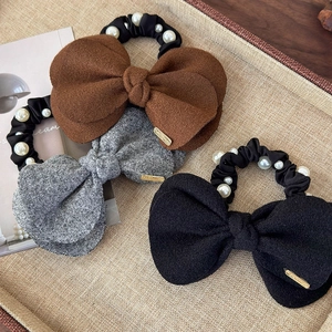 Three wool bow scrunchies with pearls and gold labels in caramel, gray and black