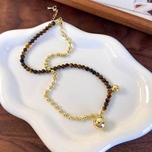 Detailed close-up of tiger eye stones and golden beads on a stylish necklace