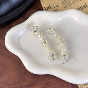 Detail of elegant pearl shoe lace charms featuring white pearls and metal rings on a plate
