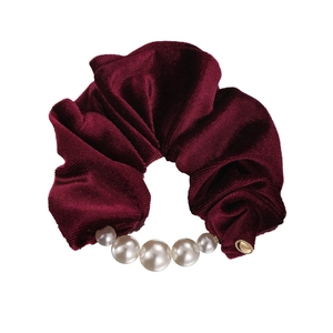 Elegant burgundy velvet scrunchie featuring white pearls and a gold metallic logo charm