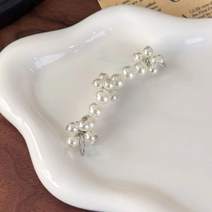 Detail view of elegant pearl flower shoe charms on a white ceramic display tray