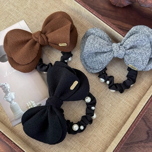 Close-up of wool bow scrunchies with pearls and handmade metal labels in three colors
