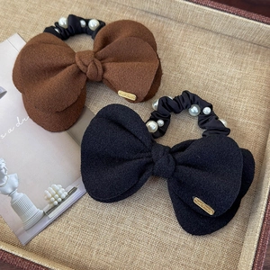 Detail of wool bow hair ties with elegant pearl accents and gold handmade tags