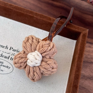 Détail d'une pince à cheveux fleur tricotée à la main kaki avec barrette effet ambre