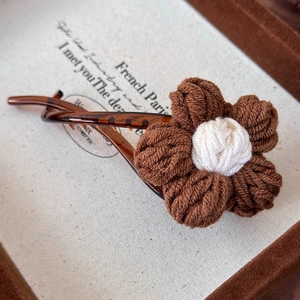 Vue détaillée d'une pince à cheveux fleur tricotée vintage avec finition en résine marron