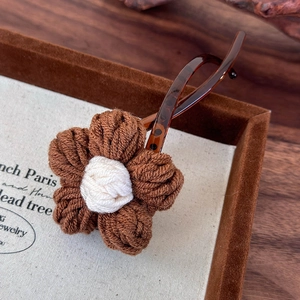 Gros plan détaillé d'une pince à cheveux fleur tricotée marron avec base en écaille