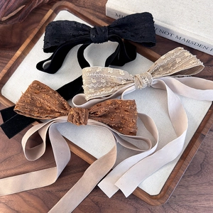 Elegant French retro bow hair clips in black, beige, and brown on a wooden tray