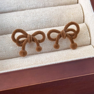 Close-up of vintage brown velvet bow earrings with soft flocking texture and ball detail