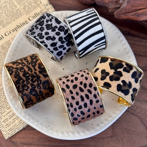 Detail showing five wide metal cuff bracelets with various animal print faux fur textures