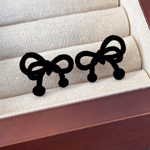 Detailed view of vintage black velvet bow earrings with spherical drops in a jewelry box