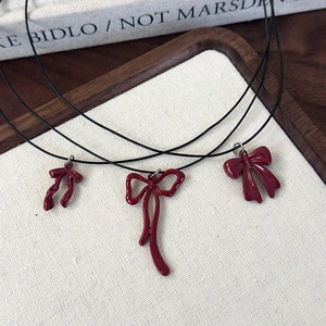 Three elegant black wax cord necklaces featuring vintage red bowknot pendants for women