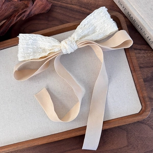 Detail of the vintage double-layer bow hair clip with lace and long champagne ribbons