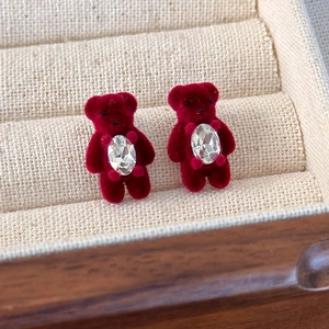 Détail de boucles d'oreilles ours floqué rouge avec incrustation de strass ovale brillant