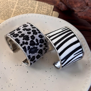 Macro shot of leopard and zebra print faux fur texture on wide metal open cuff bracelets