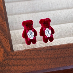 Détail de boucles d'oreilles ours floqué rouge avec cristal ovale et texture en velours