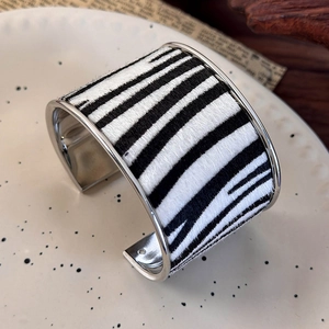Macro detail of zebra print suede finish on wide silver metallic open cuff bracelet