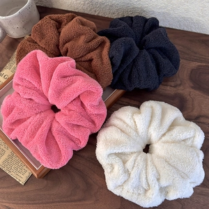 Soft fleece scrunchies set in pink, brown, black and white on a wooden background