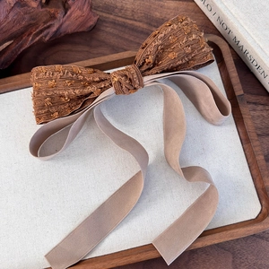 Close-up detail of vintage bow hair clip with jacquard fabric and velvet ribbons