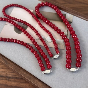 Collier de perles de verre rouges rondes avec fermoir argenté vintage sur velours gris