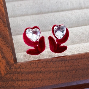 Gros plan détaillé des boucles d'oreilles tulipe en velours rouge avec cristal en forme de cœur