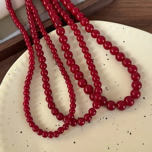 Vue détaillée de colliers de perles de verre rouge foncé en trois tailles sur plat
