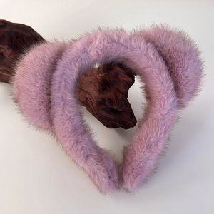 Détail de deux serre-têtes en peluche rose avec oreilles de chat sur fond en bois