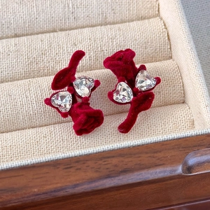 Détail macro de boucles d'oreilles fleurs en velours rouge avec cristaux de cœur