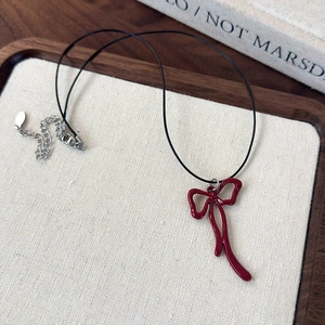 Detail of red bow pendant on black wax cord with adjustable silver chain clasp