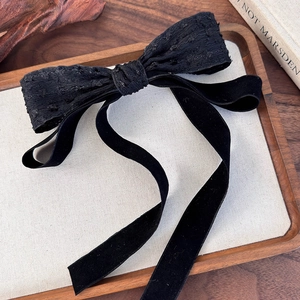 Detail of vintage Audrey Hepburn style black lace bow hair clip with velvet ribbons