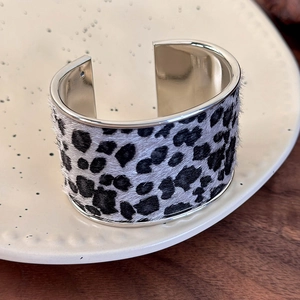 Close-up of zebra pattern faux fur cuff bracelet with polished silver metal edges on ceramic